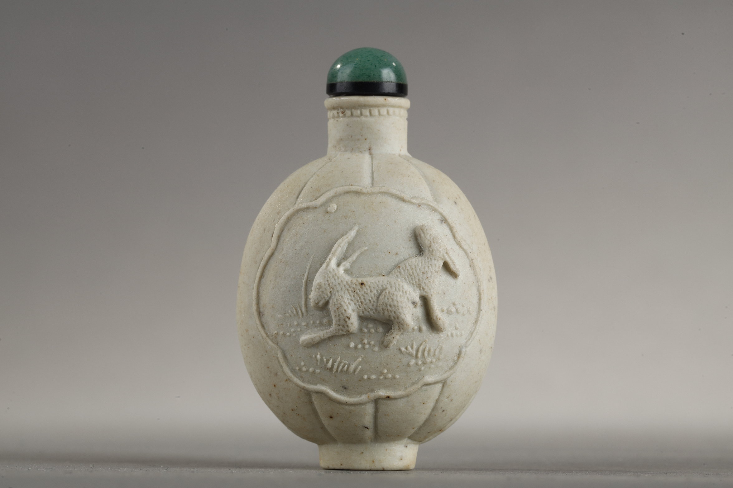 small biscuit snuff bottle (porcelain) with rabbit relief decoration on one side and loir in grapes on the other 
China 19th century 